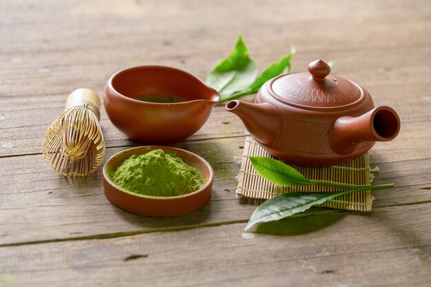 Tè verde Matcha e set da tè giapponese. Teiera di ceramica e una tazza di cottura a vapore su fondo di legno