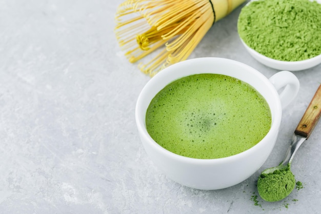 Tè verde matcha giapponese latte in tazza bianca su sfondo di pietra grigia