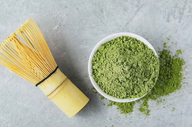 Tè verde matcha in polvere in una ciotola bianca su sfondo di pietra grigia Vista dall'alto