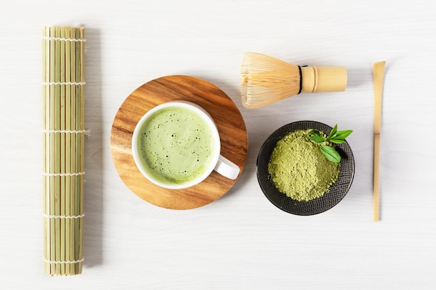 Tè verde matcha latte e accessori per il tè su sfondo bianco di legno Concetto di cerimonia del tè giapponese