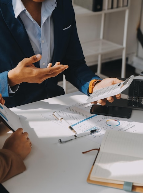 Team aziendale che lavora con un nuovo progetto di startup e discute informazioni per la strategia finanziaria con laptop e tablet digitali in una moderna sala business