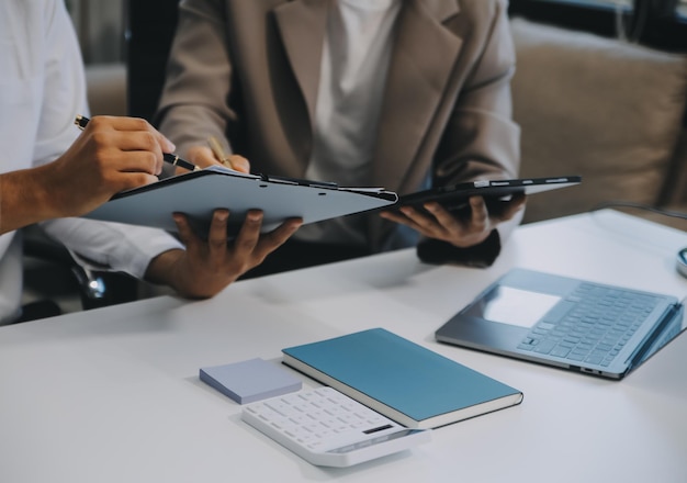 Team aziendale che lavora con un nuovo progetto di startup e discute informazioni per la strategia finanziaria con laptop e tablet digitali in una moderna sala business