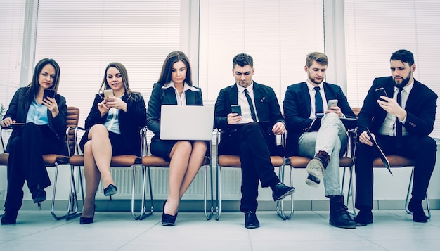 Team aziendale con laptop e smartphone seduto sul divano nella hall prima della sessione di lavoro