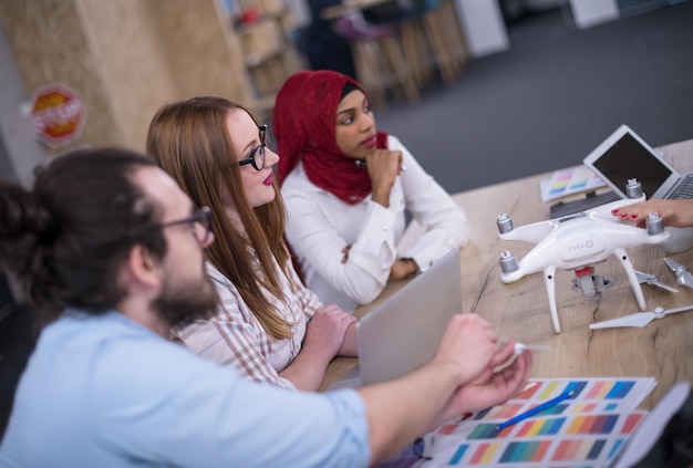 team aziendale di avvio multietnico che discute di un nuovo piano aziendale, lavora su laptop e tablet mentre apprende la tecnologia dei droni per il nuovo avanzamento del business