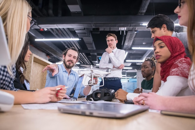 team aziendale di avvio multietnico che discute di un nuovo piano aziendale, lavora su laptop e tablet mentre apprende la tecnologia dei droni per il nuovo avanzamento del business