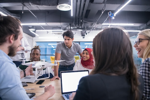 team aziendale di avvio multietnico che discute di un nuovo piano aziendale, lavora su laptop e tablet mentre apprende la tecnologia dei droni per il nuovo avanzamento del business