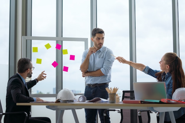 Team di architetti multietnici che lavorano su piani di costruzione in sala riunioni