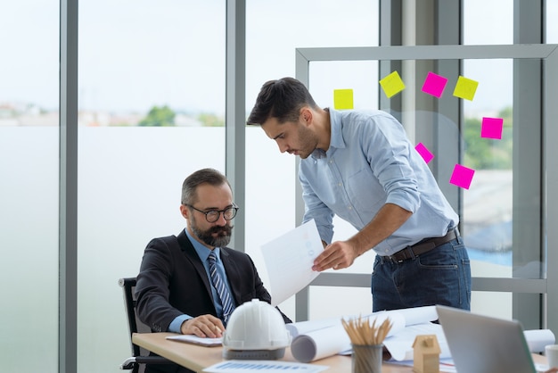 Team di architetti multietnici che lavorano su piani di costruzione in sala riunioni