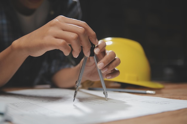 Team di architetti multietnici che lavorano su piani di costruzione nella sala riunioni Ingegneri che discutono del progetto in ufficio Uomo d'affari maturo e donna in piedi attorno al tavolo che lavorano sul progetto