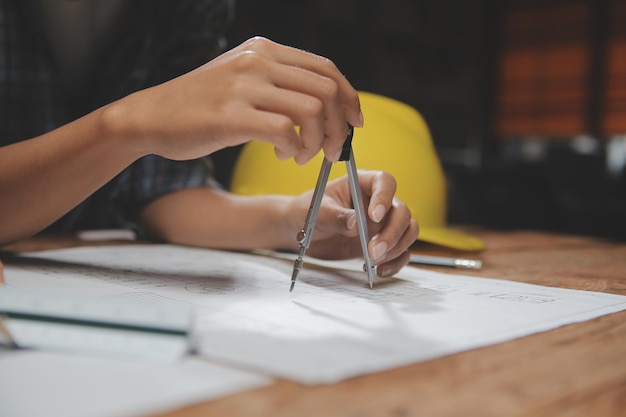 Team di architetti multietnici che lavorano su piani di costruzione nella sala riunioni Ingegneri che discutono del progetto in ufficio Uomo d'affari maturo e donna in piedi attorno al tavolo che lavorano sul progetto