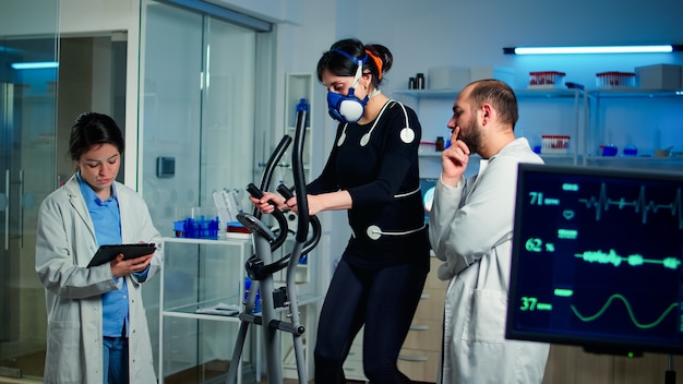Team di medici professionisti che misurano le condizioni di salute dell'atleta donna nel laboratorio sportivo scientifico