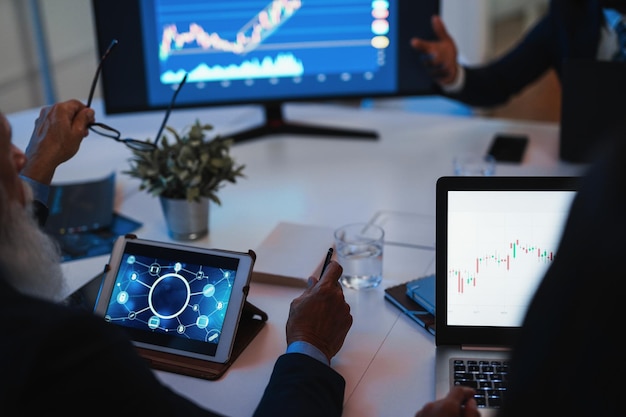 Team di operatori che effettuano analisi del mercato azionario all'interno dell'ufficio degli hedge fund Focus sullo schermo del computer destro