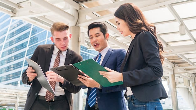 Team di uomini d'affari smart uomo e donna parla nelle ore di punta con file presenti lavoro di carta al pedone all'aperto