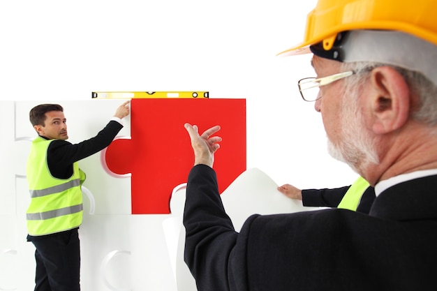 Team di uomo d'affari e lavoratori che assemblano puzzle isolato su bianco