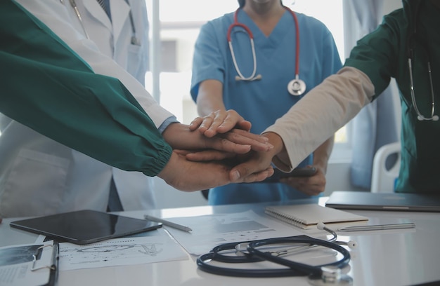 Team medico multirazziale che ha un incontro con medici in camici bianchi e scrub chirurgici seduti a un tavolo che discutono dei record di un paziente