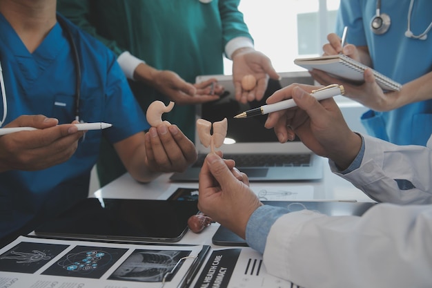 Team medico multirazziale che ha un incontro con medici in camici bianchi e scrub chirurgici seduti a un tavolo che discutono dei record di un paziente