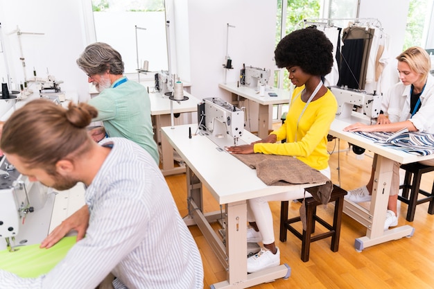 Team multietnico di stilisti al lavoro in un laboratorio di start-up di abbigliamento - Gruppo multietnico di stilisti, stilisti e sarti al lavoro su una nuova collezione