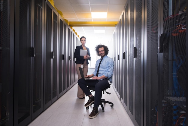 Team of young technicians working together on servers at the data center using laptop and tablet computers