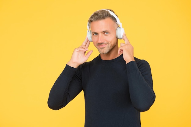 Techno moda maschile. ragazzo dall'aspetto elegante e alla moda con gli auricolari. formazione in linea. amante della musica allegro. qualità del suono. ragazzo fiducioso con le cuffie. bell'uomo ascolta canzone.