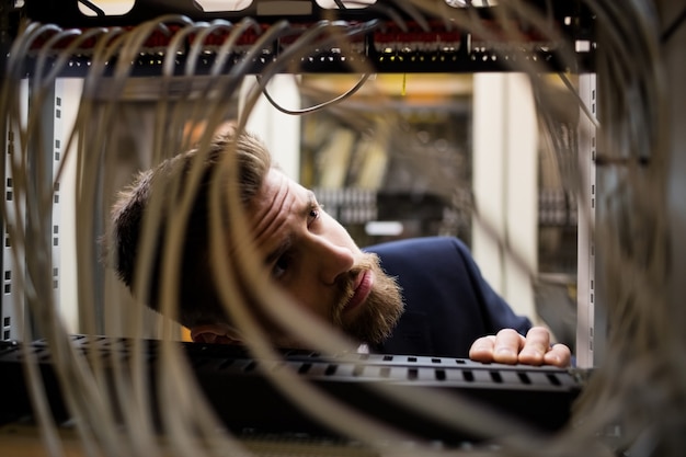 Tecnico che controlla i cavi in un server montato su rack