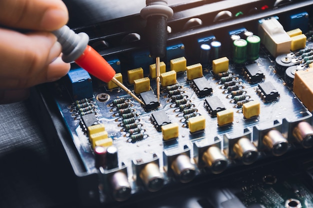 tecnico che controlla ic sul circuito con sonda multimetro