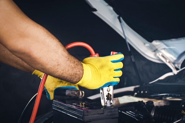 Tecnico che fissa il cavo del caricabatterie alla carica dell'accumulatore della batteria dell'auto