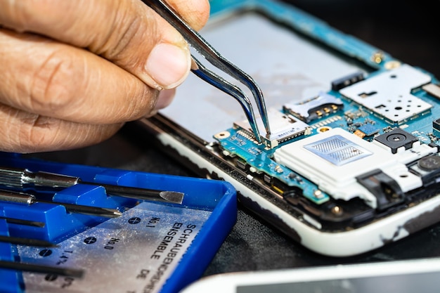 Tecnico che ripara l'interno del telefono cellulare mediante saldatore Circuito integrato il concetto di tecnologia hardware dati