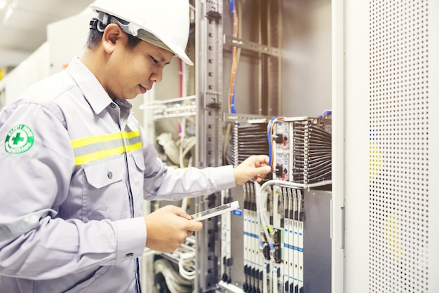 Tecnico che utilizza tablet digitale nella sala server, ripara la scheda madre controllando lo stato del collegamento di rete network