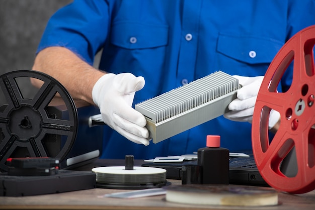 Tecnico con guanti bianchi che digitalizzano la vecchia diapositiva da 35 mm