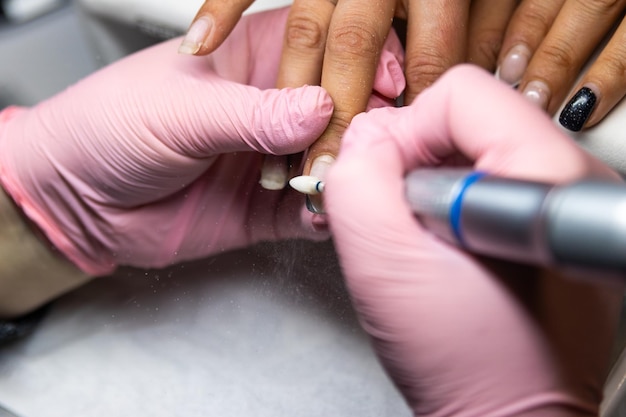 Tecnico delle unghie che usa un file elettrico durante la manicure