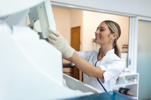 Tecnico di laboratorio che carica i campioni in un analizzatore chimico Tecnico di laboratorio femminile che carica il campione per l'analisi del test di coagulazione