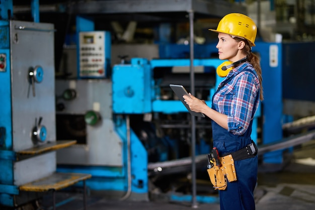 Tecnico femminile che controlla le macchine alla fabbrica