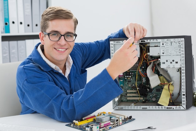 Tecnico sorridente che lavora al computer rotto