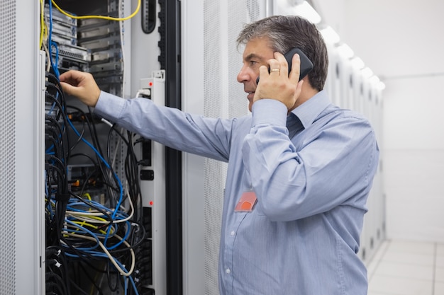 Tecnico telefonando durante la riparazione del server