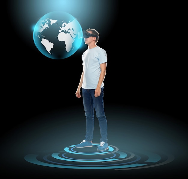 Tecnologia 3d, giochi, realtà aumentata, cyberspazio e concetto di persone - giovane felice con cuffie per realtà virtuale o occhiali 3d guardando l'ologramma del globo terrestre su sfondo nero