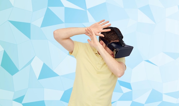 Tecnologia 3d, realtà virtuale, intrattenimento e concetto di persone - giovane spaventato con cuffie per realtà virtuale o occhiali 3d che giocano e coprono da qualcosa su sfondo basso poli