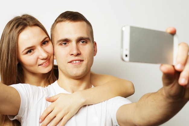 Tecnologia amore e concetto di amicizia coppia sorridente con smartphone selfie e divertimento Studio girato su sfondo bianco