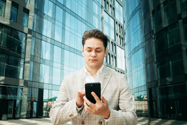 Tecnologia aziendale e concetto di persone giovane uomo d'affari con smartphone su edificio per uffici