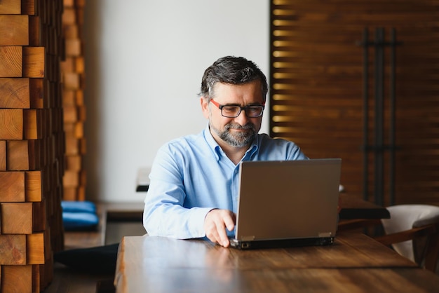 Tecnologia aziendale e concetto di persone Uomo d'affari senior con computer portatile che beve caffè al caffè moderno