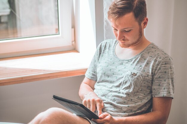Tecnologia, casa - concetto di stile di vita ravvicinata di un uomo che lavora con il tablet PC e seduto sulla sedia a casa