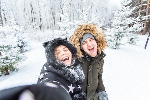 Tecnologia di amore di stagione e concetto di svago coppia felice che si fa selfie con lo smartphone durante l'inverno