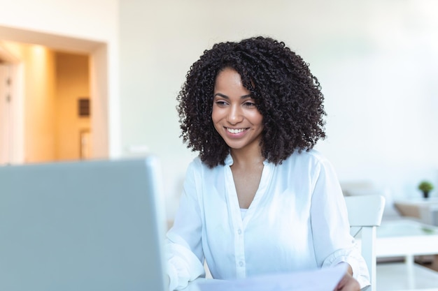Tecnologia di lavoro a distanza e concetto di persone giovane donna d'affari sorridente felice con computer portatile e documenti che lavorano a casa durante la crisi sanitaria di Covid19