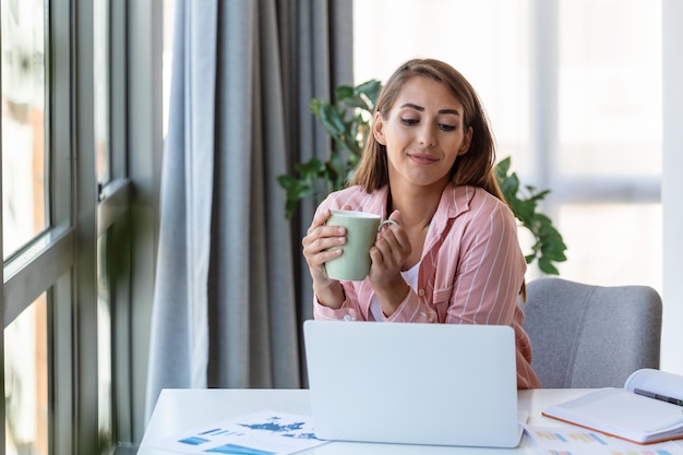 Tecnologia di lavoro a distanza e concetto di persone giovane donna d'affari sorridente felice con computer portatile e documenti che lavorano a casa in ufficio