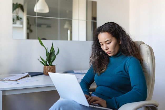 Tecnologia di lavoro remoto e concetto di persone Giovane donna d'affari asiatica focalizzata con computer portatile e documenti che lavorano in ufficio a casa