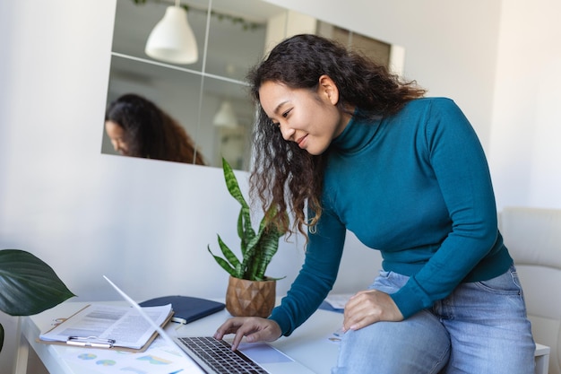 Tecnologia di lavoro remoto e concetto di persone giovane donna d'affari asiatica sorridente felice con computer portatile e documenti che lavorano in ufficio a casa