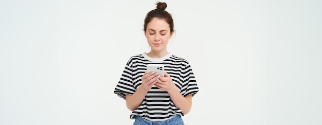 Tecnologia e stile di vita giovane donna in piedi su sfondo bianco con lo smartphone