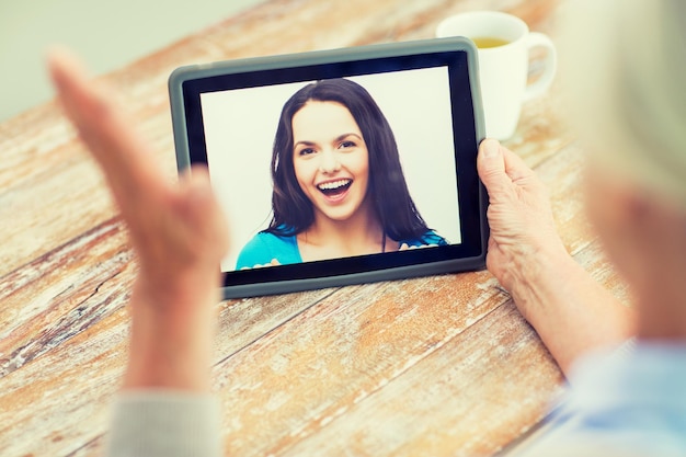 tecnologia, età, ricordi e concetto di persone - donna anziana felice con computer tablet pc che guarda foto o che ha chat video con la nipote a casa