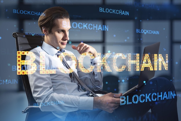 Tecnologia finanziaria blockchain e concetto di fintech con un giovane uomo d'affari fiducioso che utilizza laptop e blockchain digitale firmano la doppia esposizione