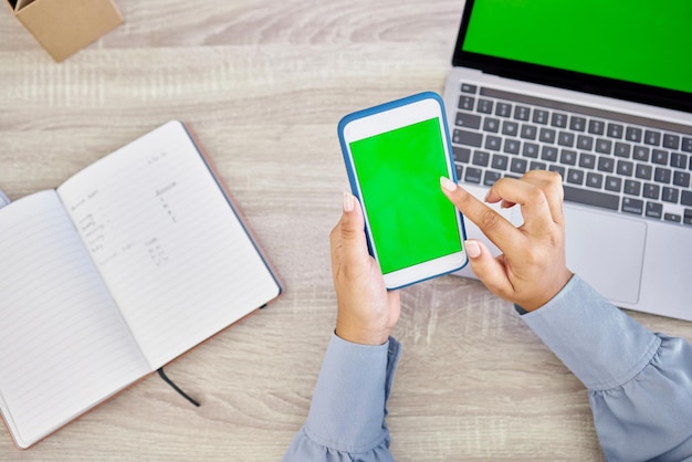 Tecnologia mani di donna con smartphone e schermo verde su laptop con notebook per la ricerca Pianificazione o mockup spazio comunicazione online o internet e vista superiore della persona femminile in ufficio