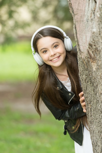 Tecnologia per bambini. Bambino felice indossare le cuffie all'aperto. La piccola ragazza ascolta musica in cuffia. Proteggere l'udito. Cuffie con cancellazione del rumore. Nuova tecnologia. Cuffie che tuo figlio apprezzerà.